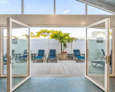 Glass doors opening to the outdoor sundeck with blue loungechairs